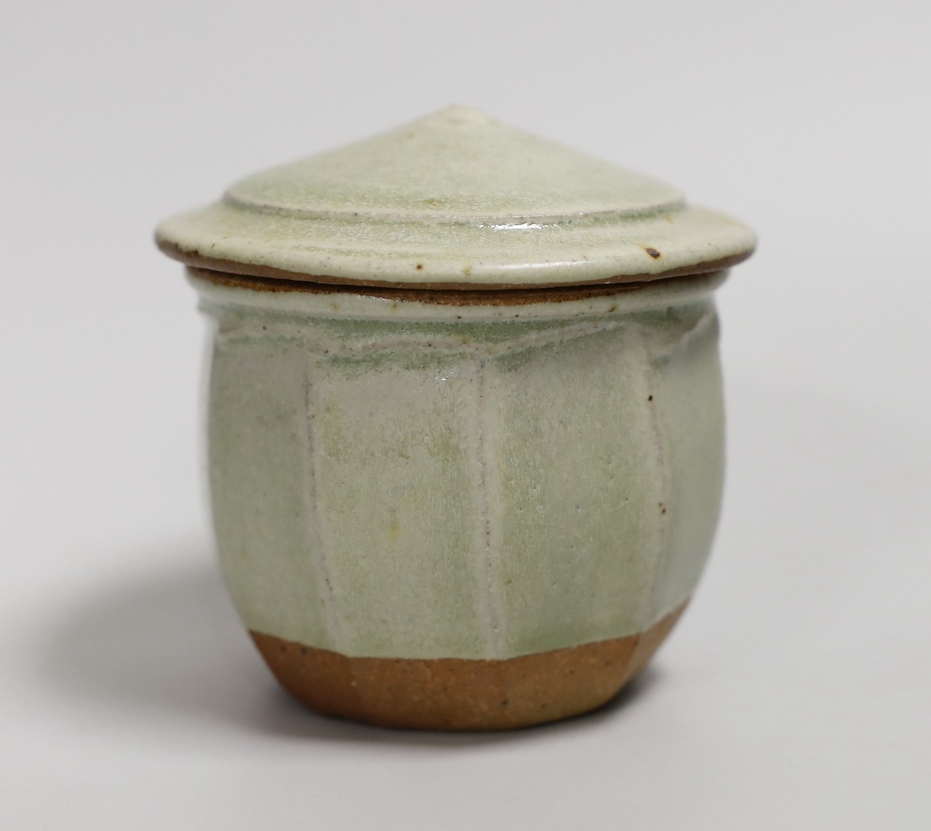 Richard Batterham (1936 – 2021), a cut sided stoneware jar and pointed cover with sage coloured glaze. 10.5cm high
